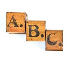 three wooden blocks with the letters abc and c in black ink on them, against a white background