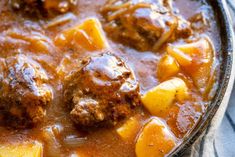 meatballs and potatoes are in a stew with gravy on the side, ready to be eaten