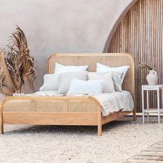 a bed with pillows and blankets on top of it next to a plant in front of a wall