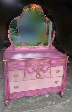 a pink dresser with a mirror on top of it