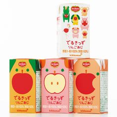 three boxes with different types of juices in them on a white surface, each containing an apple