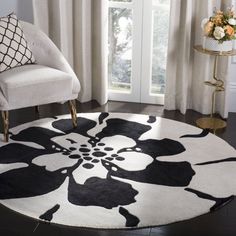 a black and white rug in a living room next to a chair with flowers on it