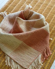 an orange and beige blanket laying on top of a woven mat