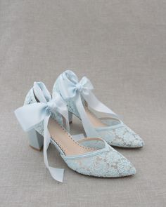 a pair of blue shoes with bows on the toe and heels that are decorated with lace