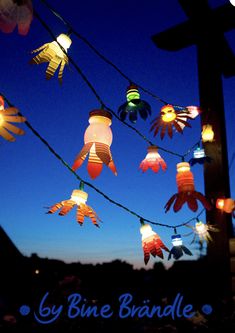 colorful paper lanterns are strung up in the night sky with words, by bine bandle