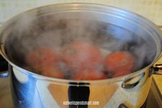 a pot filled with lots of oranges on top of a stove next to a burner