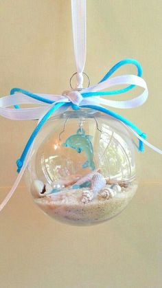 a glass ornament with a blue ribbon hanging from it's side on a table