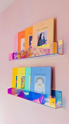 two shelves with books on them against a pink wall