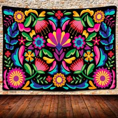 a colorful tapestry hanging on the wall in front of a brick wall with wood flooring