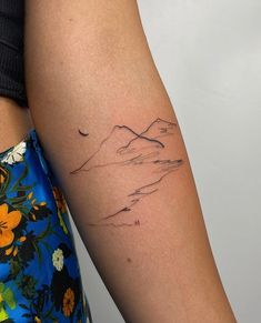 a woman's arm with a mountain tattoo on the left side of her arm