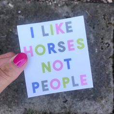 someone holding up a sticker that says i like horses not people on the front