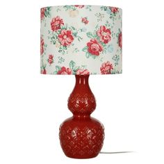 a red table lamp with a flowered shade on the base and a floral print lampshade