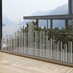 an empty room with wooden flooring and large glass windows overlooking the mountains in the distance