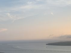 a boat is out on the water at sunset or dawn with some clouds in the sky