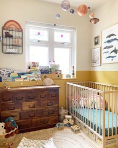 a baby's room with a crib, dresser and window