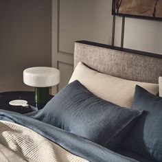 a bed with blue and white pillows on top of it next to a night stand