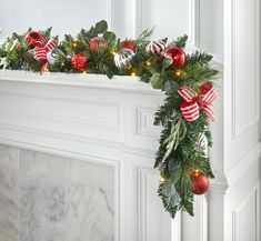 a christmas garland with red and green ornaments hanging from the mantel above a fireplace