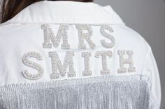 the back of a woman's white jacket with silver sequins on it