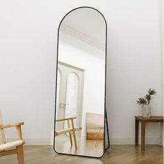 a mirror sitting on top of a wooden floor next to a chair