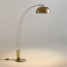 a floor lamp with a metal base and a gold shade on the top, against a white background