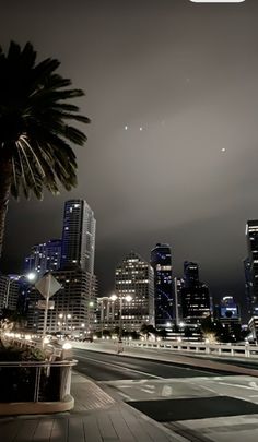 the city skyline is lit up at night with palm trees and buildings in the foreground