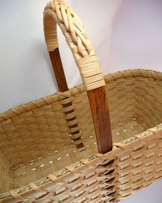 a woven basket with wooden handles hanging on a wall