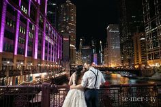 a bride and groom kissing in front of the chicago river at night