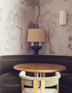 a living room with a couch, table and lamp in front of a wallpapered tree