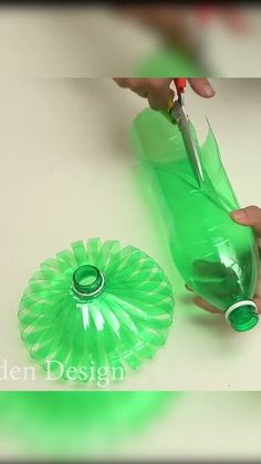 a person is cutting plastic with scissors on a counter top next to a green bottle