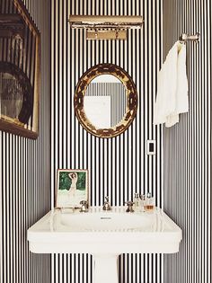 a white sink sitting under a bathroom mirror next to a wall mounted faucet