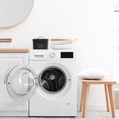 a white washer sitting next to a wooden stool