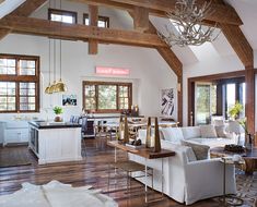 a living room filled with white furniture and wooden beams on the ceiling, along with windows