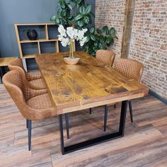 a wooden table with chairs around it in front of a brick wall and potted plant