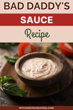 a small wooden bowl filled with sauce on top of a cutting board next to tomatoes and basil