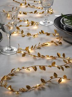 the table is set with silverware and gold leaf garlands, which are lit up by fairy lights