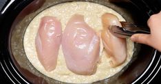 two pieces of chicken being cooked in a crock pot with rice and broth