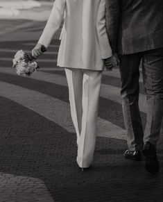 a man and woman walking down the street holding hands with each other, both dressed in white