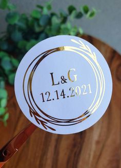 a close up of a wedding sticker on a wooden table with greenery in the background