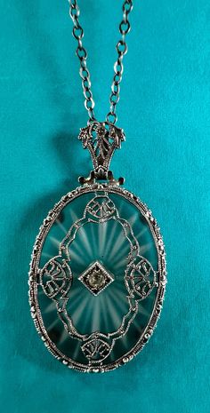 This delicate pendant is typical of the style of camphor glass pendants often described as "art deco" here on Etsy, but the style seems more Victorian or Edwardian.  Regardless, it is beautifully preserved, with the camphor glass piece locked securely in place by sterling prongs, and the diamond setting pinned into place.  The chain is labelled "sterling" as you can see in the micro photos, so I'm assuming the frame of the pendant is silver as well. The pendant is about an inch long and the chain is 20". Art deco would place this piece in the 1920's, but I'm certain I remember at one point Momma telling me that this was Grandma Heizel's, and she may have brought it with her from Germany.  That would place is more like the late 1800's or very early 1900's, and would explain the more traditi Antique Oval Cabochon Pendant Necklace, Antique Etched Oval Pendant Necklace, Furnace Glass Necklace, Camphor Glass Jewelry, Vintage Silver Glass Necklace, Diamond Settings, Glass Pendants, Glass Collection, Sterling Silver Pendants