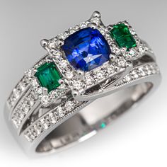 This mesmerizing ring features one (1) prong set cushion cut natural sapphire, two (2) prong set emerald cut natural emeralds, and seventy (70) prong set round brilliant cut diamonds. The ring measures 9.1mm at the top and rises 8.0mm above the finger, tapering to 4.4mm wide and 1.6mm thick at the base of the shank. It is crafted in 18k white gold and is currently a size 7.5. Platinum Emerald Cut Multi-stone Diamond Ring, Diamond Multi-stone Cushion Cut Rings, Cushion Cut Multi-stone Diamond Rings, Cushion Cut Diamond Rings With Multi-stone, Luxury Cushion Cut Multi-stone Jewelry, Luxury Multi-stone Cushion Cut Jewelry, Emerald Cut Multi-stone Platinum Rings, Elegant Multi-stone Sapphire And Emerald Ring, Elegant Multi-stone Emerald Ring In Platinum