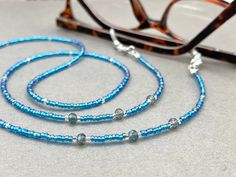 Dainty and bohemian eyeglass necklace chain in blue/Turquoise tones, made with Preciosa Czech crystal seed beads tiny silver plated crystal seed beads and delicate light blue cubic zirconia crystal beads. Paired with grey blue cubic zirconia crystal beads, this handmade eyeglass chain will definitely create a unique look.  The eyeglass lanyard is made on strong quality beading wire with silver plated wire guardians that protect the quality eyeglass holder grips. The necklace is ended with spring Blue Glasses Chains With Colorful Beads For Beach, Blue Beaded Glasses Chain For Beach, Blue Beaded Chain Glasses Chains With Round Beads, Blue Glasses Chain With Colorful Beads As Gift, Blue Glasses Chain With Colorful Beads For Gift, Blue Glasses Chains With Colorful Beads As Gift, Blue Glasses Chains With Colorful Beads For Gift, Blue Beaded Glasses Chains, Blue Glasses Chains With Round Beaded Chain