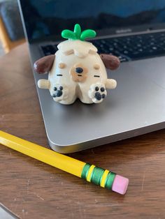 a toy dog sitting on top of a laptop computer next to a yellow crayon pencil