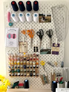 a peg board with scissors, thread, and other crafting supplies on it's side