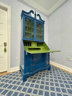 a blue desk with a green top in the middle of a room next to a white door