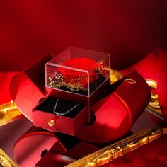 a red rose in a glass box sitting on top of a gold plated tray