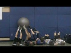 a group of young people are playing with a ball in a gym while one person is on the floor