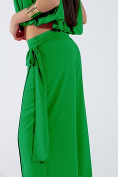 Introducing our Wide Green Pants Overlay Skirt, a stunning and versatile piece perfect for adding a touch of elegance to your party attire. This maxi-length overlay skirt features wide legs and a relaxed fit, providing both comfort and sophistication for any occasion.  Crafted from lightweight chiffon fabric, this overlay skirt drapes beautifully and flows with every movement. The knot detail at the side adds a chic and stylish touch, while the zip side closure ensures easy wear.  Perfect for parties or special events, this skirt can be paired with a variety of tops to create different looks. Made from 100% polyester with a polyester lining, it is durable and easy to care for, making it a practical choice for your wardrobe.  Our model is wearing size S, but the S-M-L sizing corresponds to Chiffon Pants, Overlay Skirt, Party Attire, Skirt Jumpsuit, Scarf Headband, Chic Top, Green Pants, Wide Legs, Romper Pants