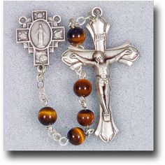 Adorned with brown and gold semi precious stones, the 6 mm Genuine Gem Stone Tiger Eye Rosary makes a fierce statement in religious accessories. Matching silver tone accents bring out the various hues of each bead, creating a lovely article of the faith to be placed in an equally dainty giftbox. Brown Crucifix Jewelry Gift, Brown Crucifix Jewelry For Gifts, Spiritual Nickel-free Brown Jewelry, Brown Beaded Rosary With Cross Shape, Brown Beaded Cross Rosary, Brown Beaded Spiritual Rosary, Brown Crucifix Spiritual Jewelry, Brown Beaded Cross-shaped Rosary, Brown Spiritual Crucifix Jewelry