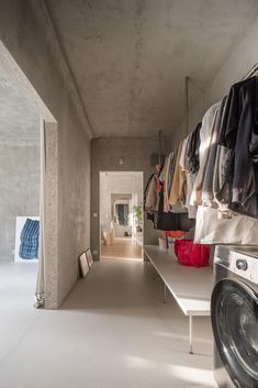 a room that has some clothes hanging on the wall and a washer in front of it