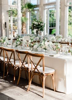 a long table with white flowers and greenery is set up for a formal dinner